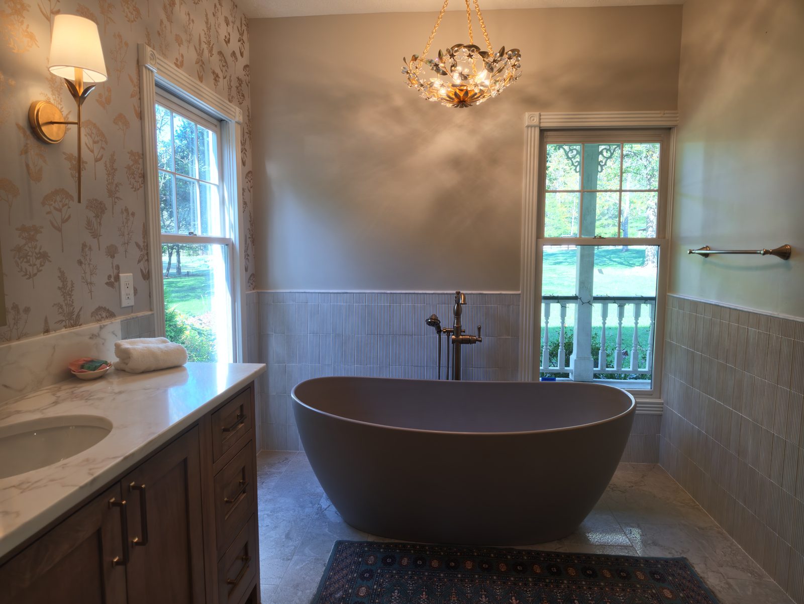 Freestanding soaking tub under glass chandelier with fluted tile wainscot Noblesville IN