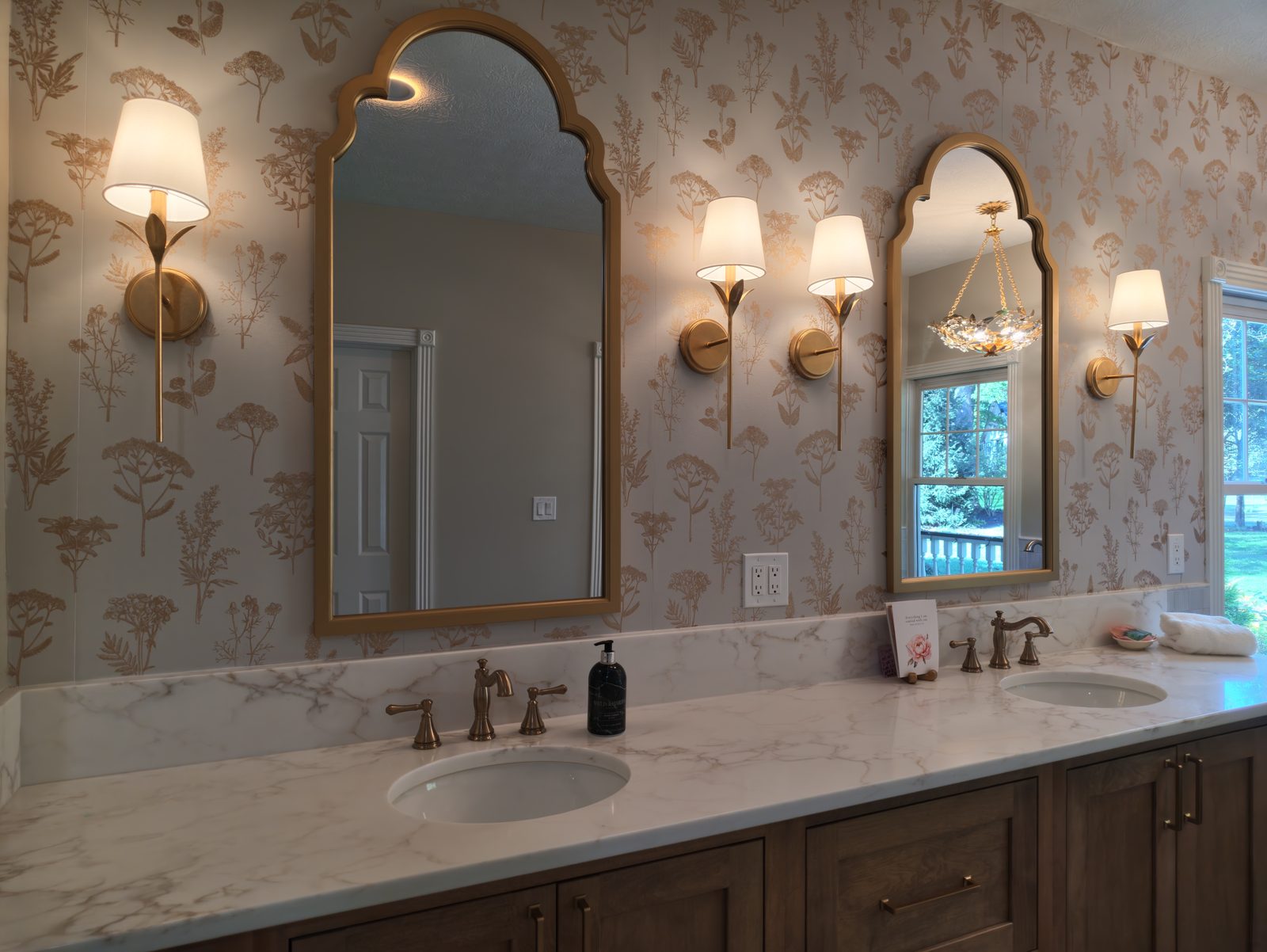 Stained oak double vanity with gold arched mirrors and botanical toile wallpaper Noblesville Indiana
