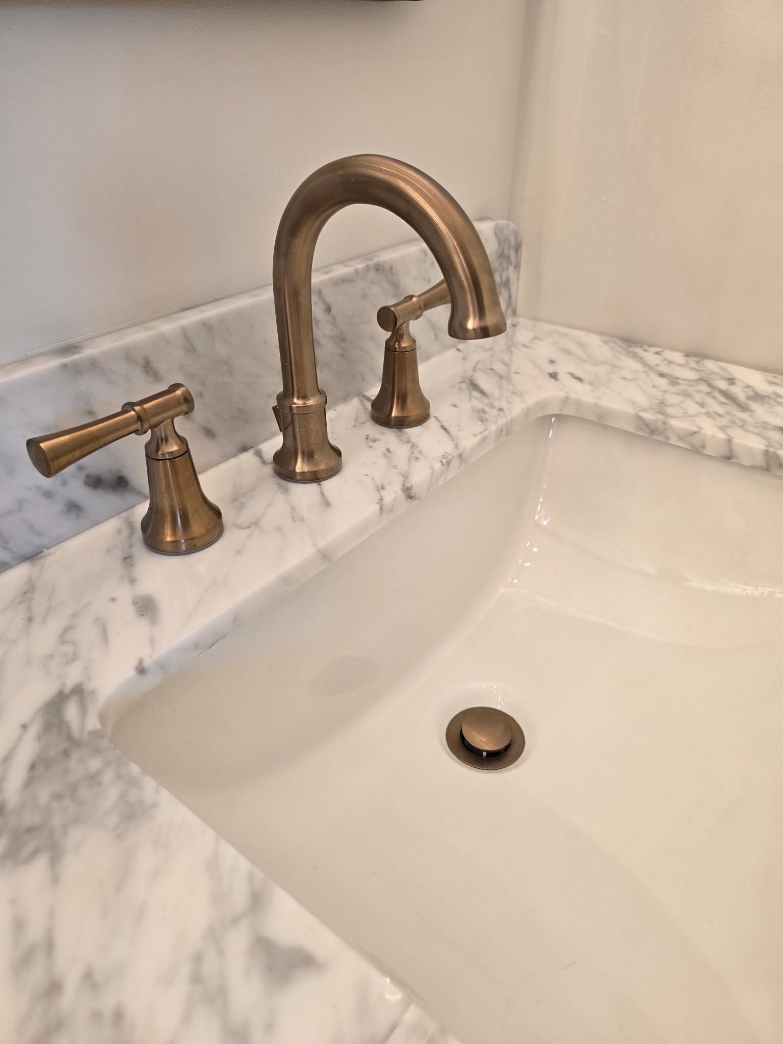 Champagne bronze widespread faucet on marble vanity top Fishers IN