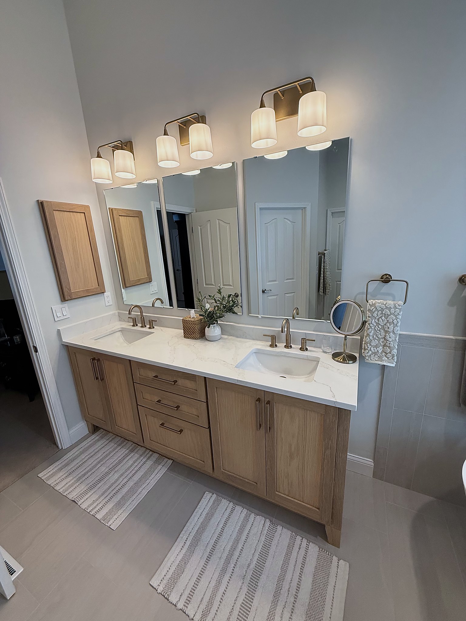 White oak double vanity with quartz countertop and champagne bronze fixtures primary bathroom Fishers IN