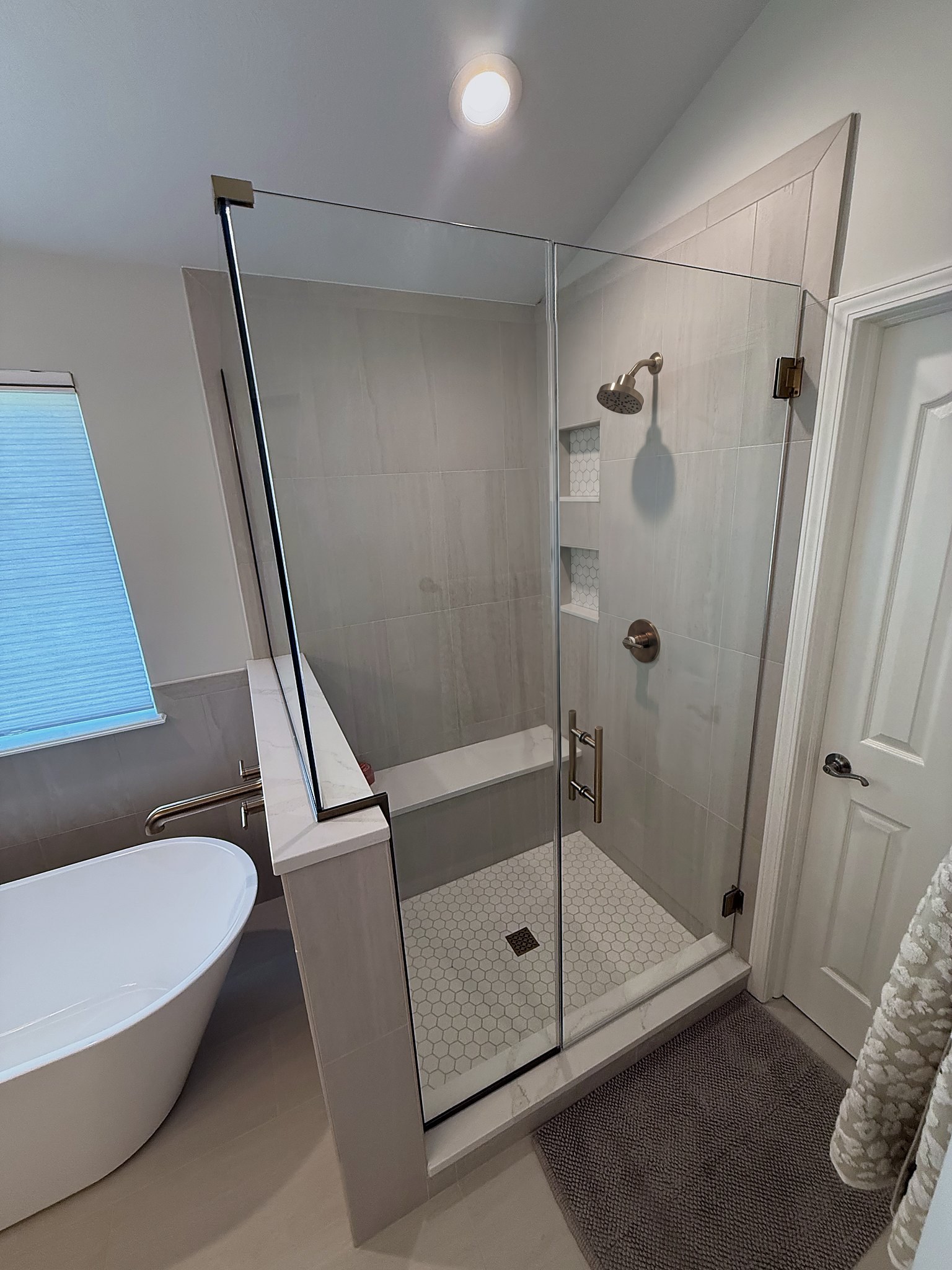 Frameless glass shower with built-in bench and hexagon mosaic floor Fishers IN