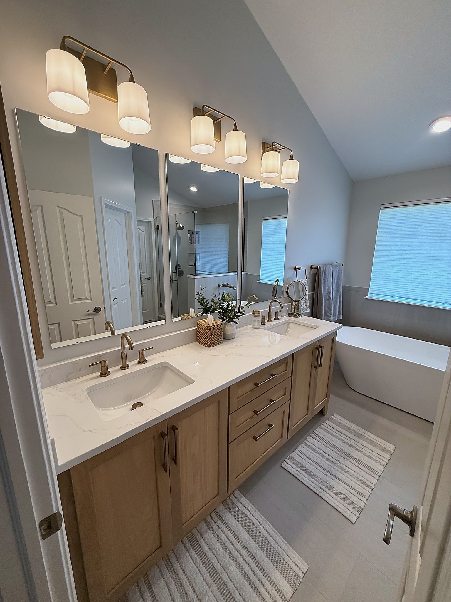 White oak vanity with dual mirrors and fabric shade sconces primary bathroom Fishers Indiana