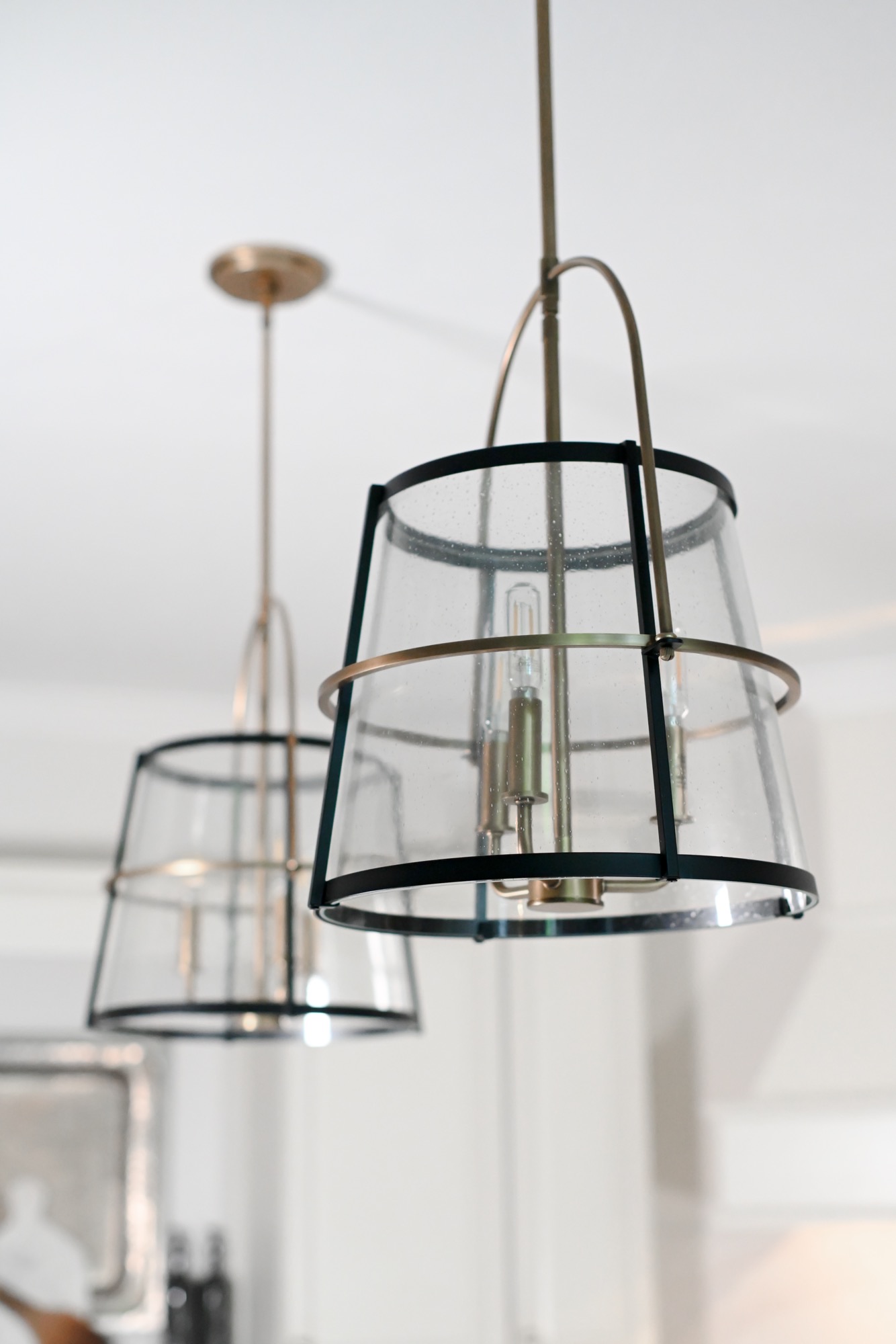 Seeded glass lantern pendants in matte black and brass over kitchen island Zionsville Indiana